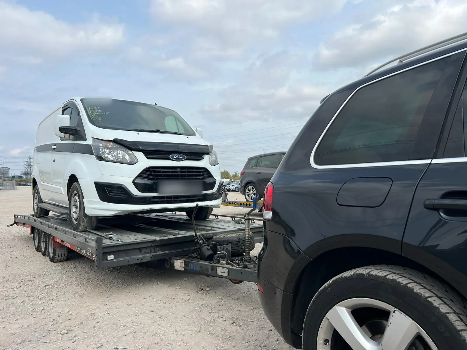 White Ford Transit Custom van loaded on a triple-axle car trailer