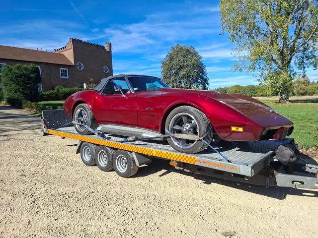 Red classic Corvette convertible strapped down on the car trailer